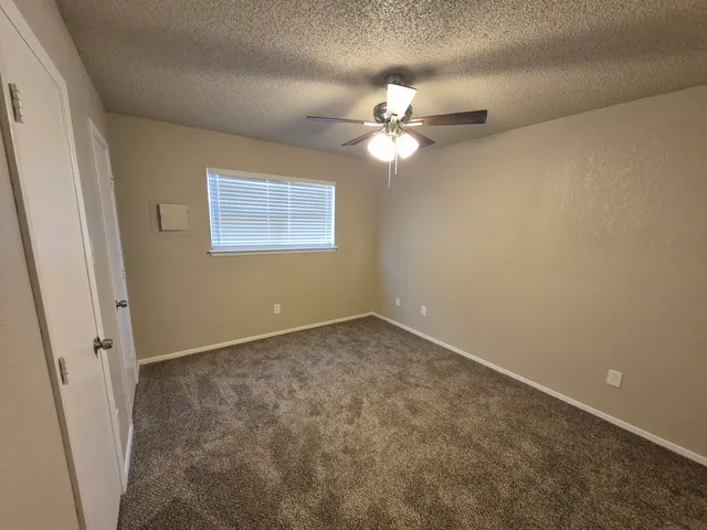 an empty room with a window and chandelier fan