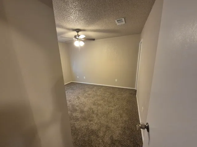 an empty room with a ceiling fan and a window
