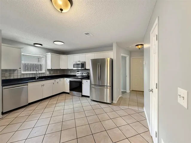 a large white kitchen with a stove a sink dishwasher and a refrigerator with wooden floor