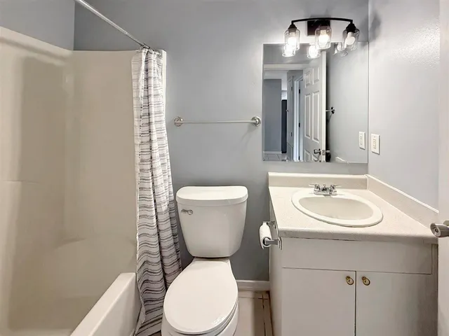 a bathroom with a sink a toilet a mirror and shower curtain
