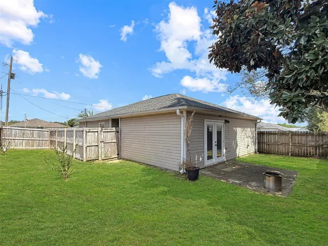 a backyard of a house with large trees and table and chairs