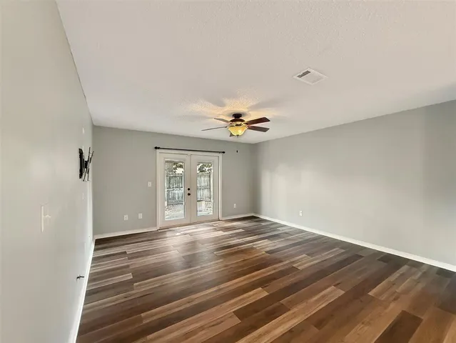 a view of an empty room with window and wooden floor