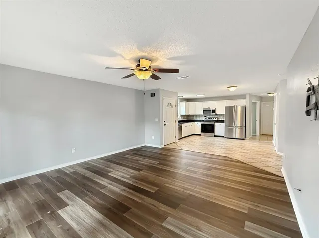 a view of kitchen and empty room with wooden floor