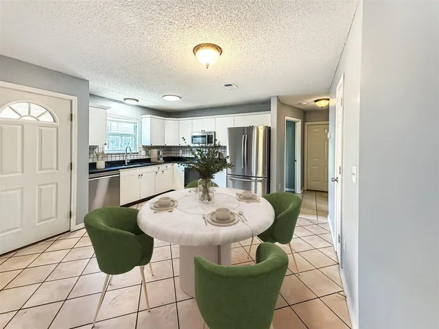 a kitchen with stainless steel appliances kitchen island granite countertop a sink a stove a dining table and chairs