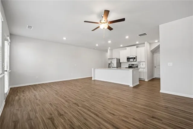 a view of a kitchen with a sink wooden floor and a ceiling fan