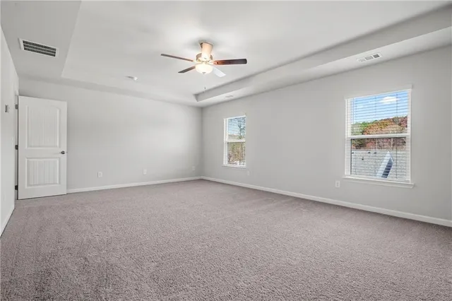 an empty room with windows and fan