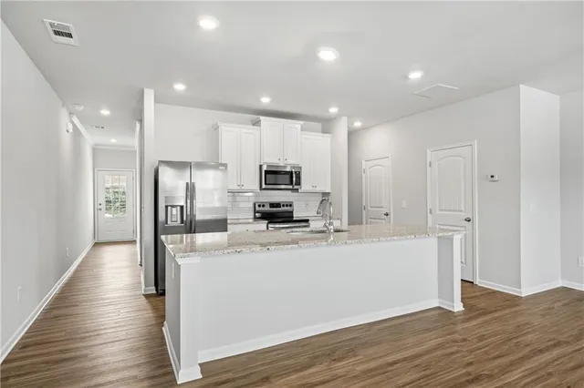 a large kitchen with stainless steel appliances a refrigerator and a stove top oven