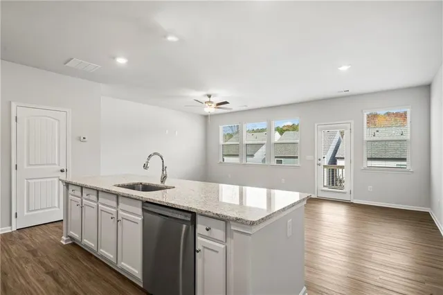 a large white kitchen with a sink and dishwasher with wooden floor