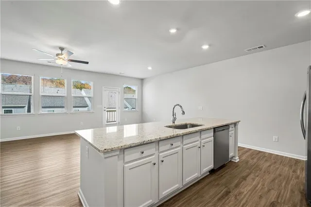 a kitchen with stainless steel appliances granite countertop a sink dishwasher and a stove with wooden floor