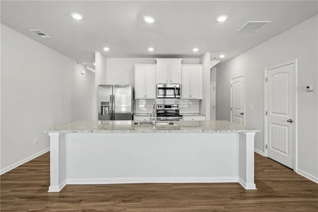 a view of kitchen with stainless steel appliances granite countertop refrigerator sink and cabinets