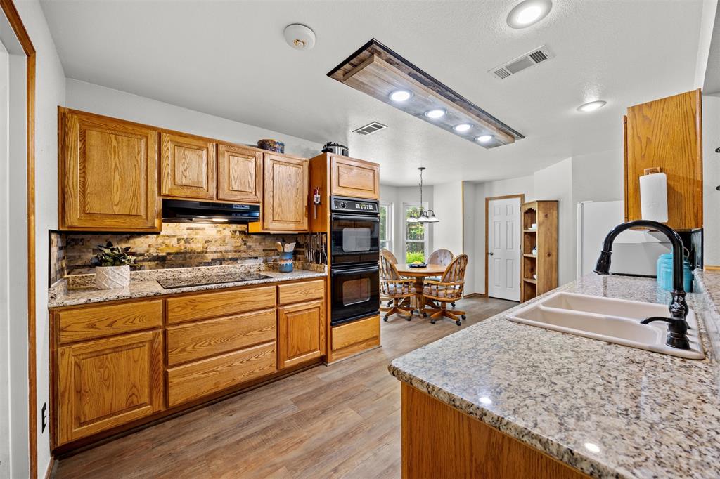 881 Wild Road Van Alstyne, TX 75495 - Photo 11 of 40 a kitchen with stainless steel appliances granite countertop a sink dishwasher stove and refrigerator with wooden floor
