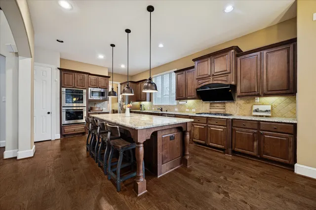 a kitchen with stainless steel appliances granite countertop a stove a sink and a refrigerator