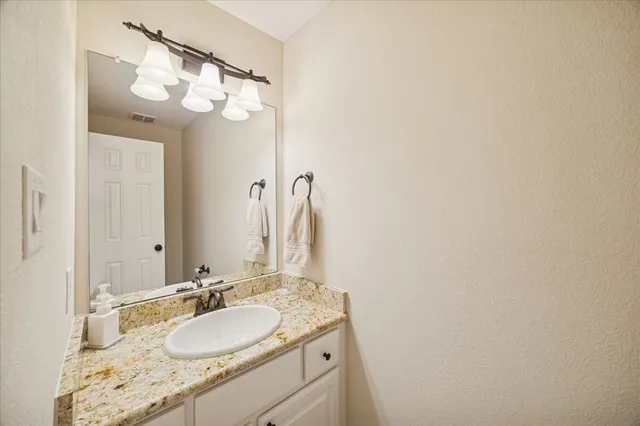 a bathroom with a granite countertop sink and a mirror