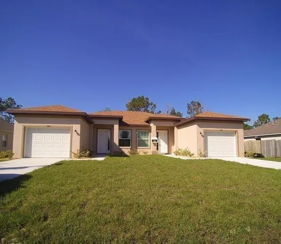 a view of a house with a big yard and large tree