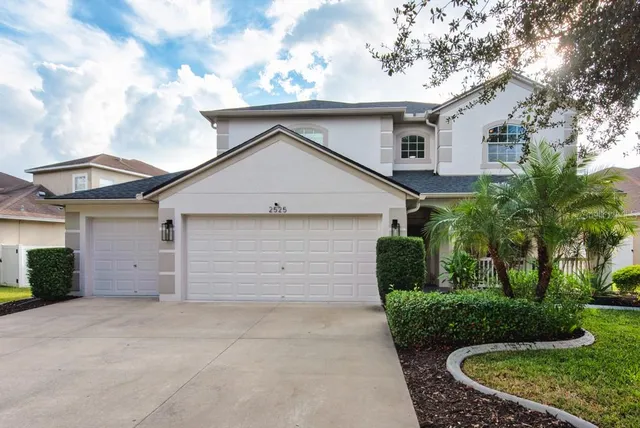 a view of a white house next to a yard and palm trees