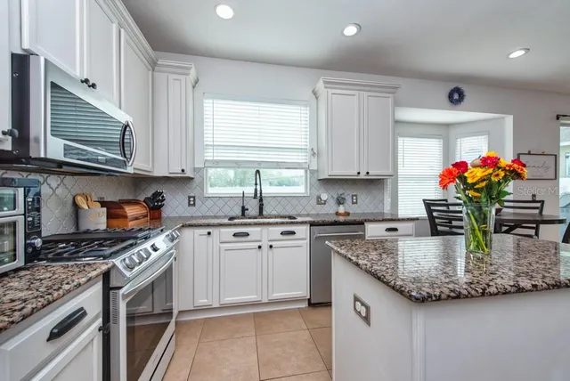 a kitchen with kitchen island granite countertop stainless steel appliances a stove sink and cabinets