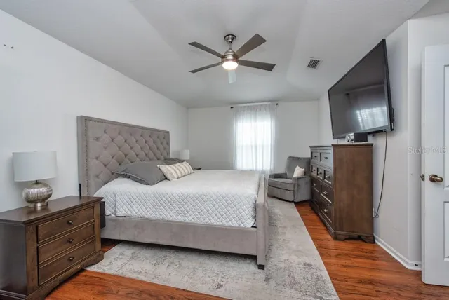a bedroom with a bed and a flat tv screen on dresser