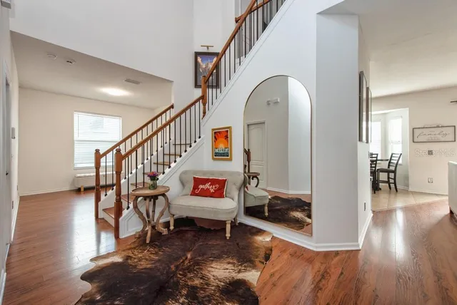 a living room with couches and a dining table with wooden floor