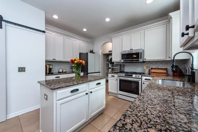 a kitchen with stainless steel appliances granite countertop a refrigerator sink stove microwave and cabinets