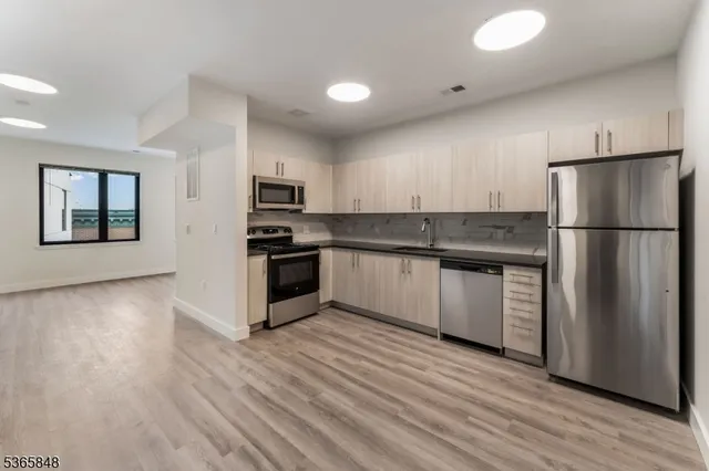 a kitchen with granite countertop a refrigerator and a stove top oven