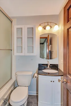 a bathroom with a granite countertop toilet sink and mirror