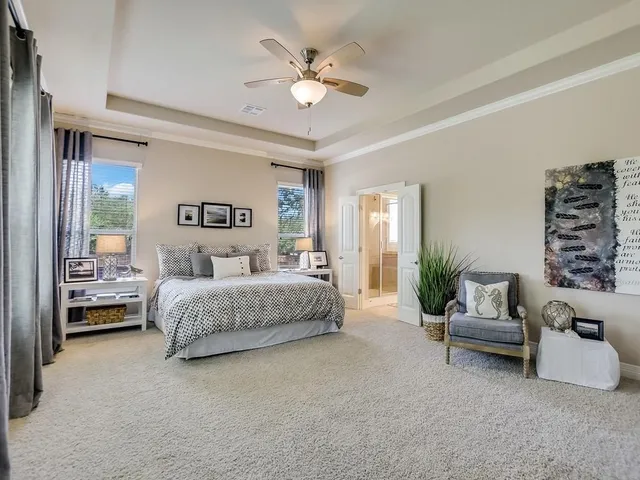 a spacious bedroom with a bed couch and windows