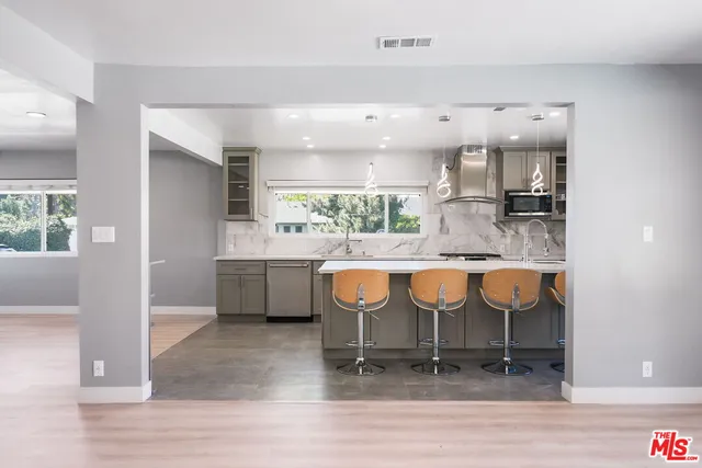 a kitchen with stainless steel appliances kitchen island granite countertop a table chairs in it and wooden floors