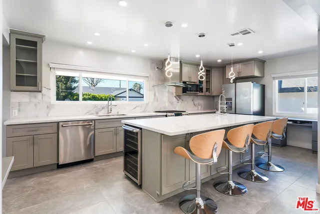 a kitchen with kitchen island stainless steel appliances a sink and cabinets
