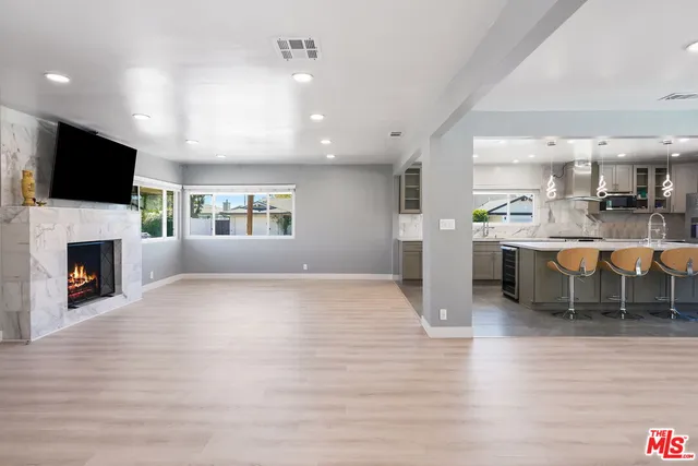 a room with stainless steel appliances kitchen island granite countertop a stove and a fireplace