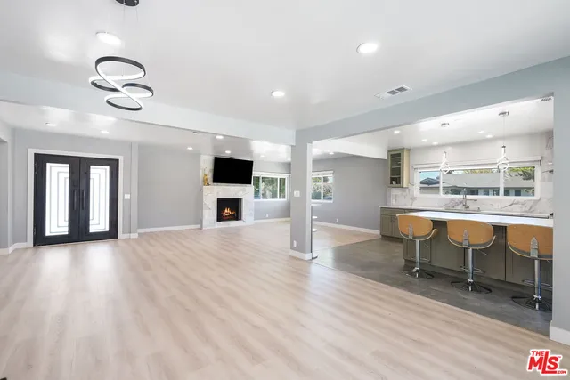 an open kitchen with wooden floor and chairs