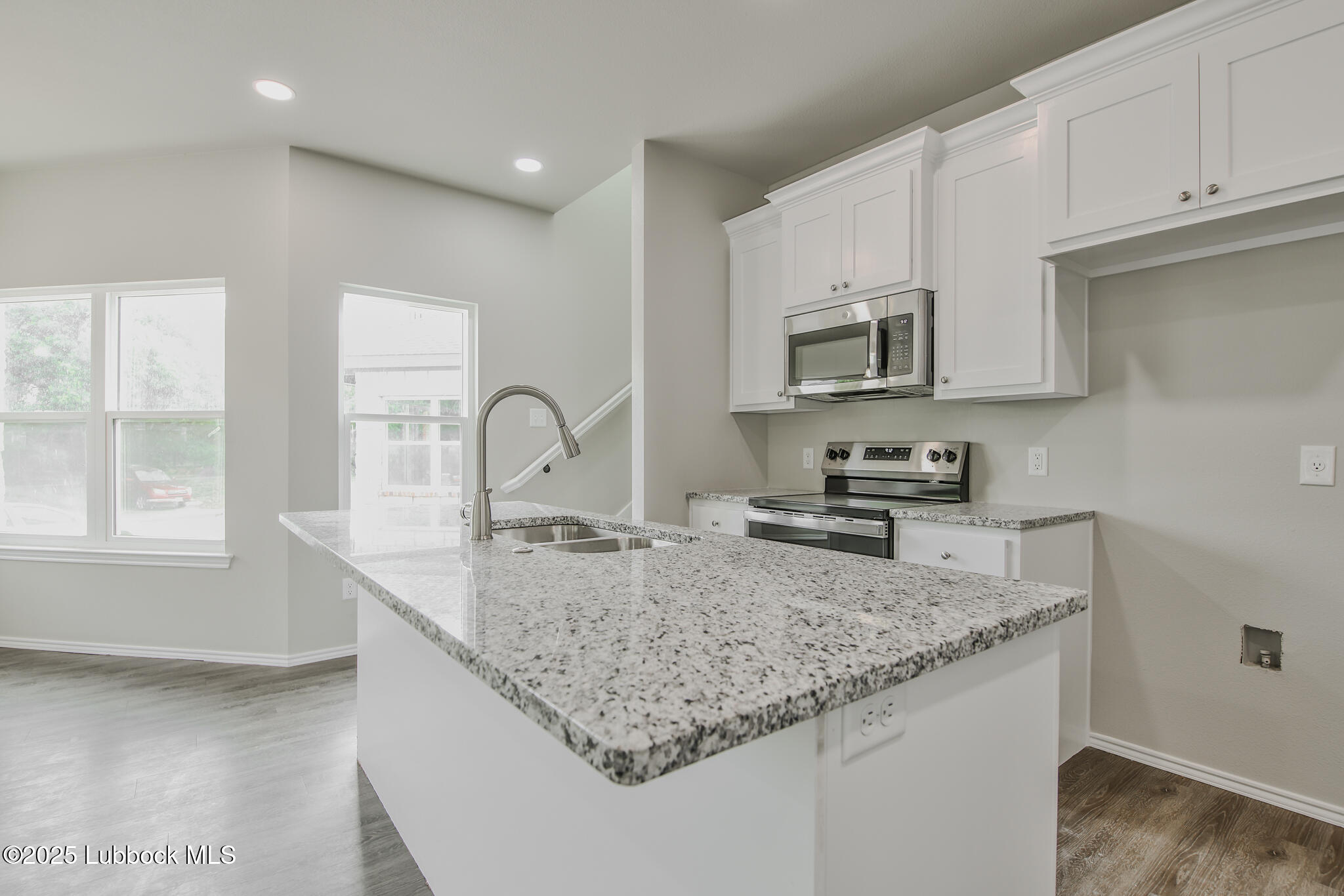 3115 74th Street Lubbock, TX 79423 - Photo 10 of 36 a kitchen with granite countertop a sink a stove and cabinets