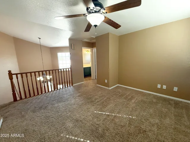 a view of an empty room with a chandelier fan