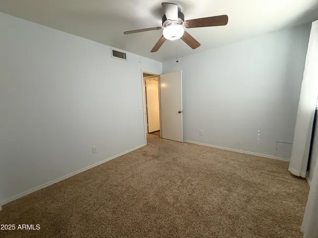 an empty room with a fan & a window