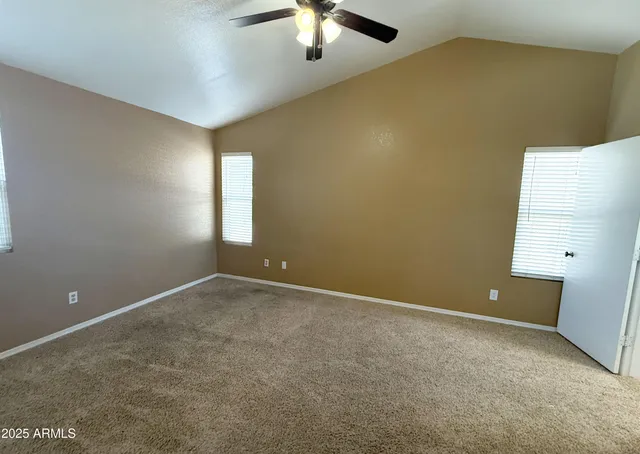 an empty room with a chandelier fan and windows