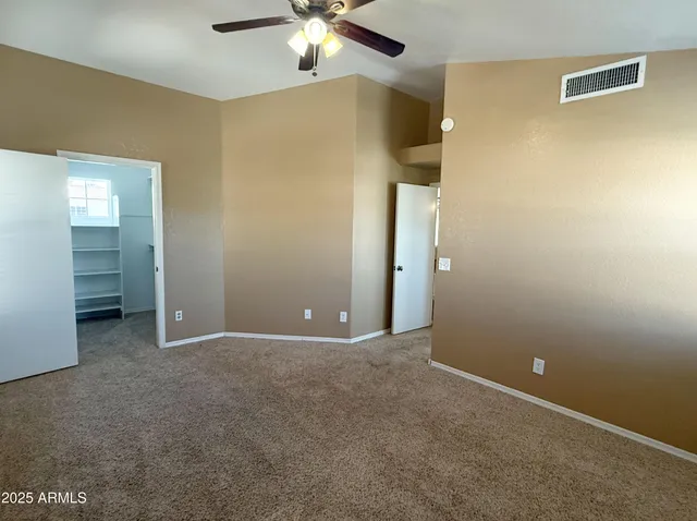 a view of an empty room with a chandelier fan