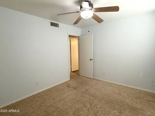 an empty room with a chandelier fan and closet