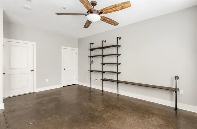 an empty room with windows and ceiling fan