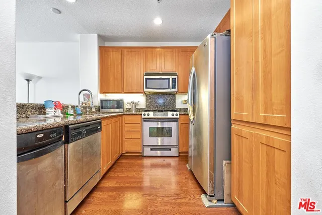 a kitchen with granite countertop a refrigerator and a stove top oven