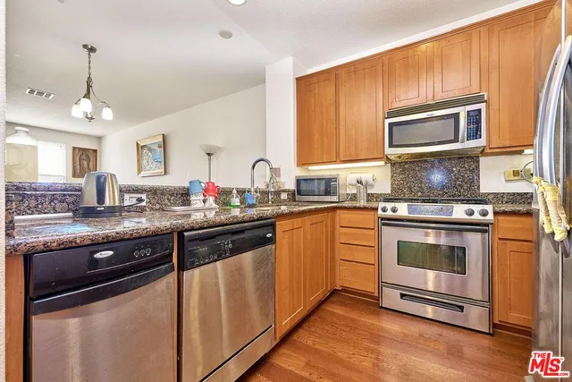 a kitchen with stainless steel appliances granite countertop a stove a sink and a microwave