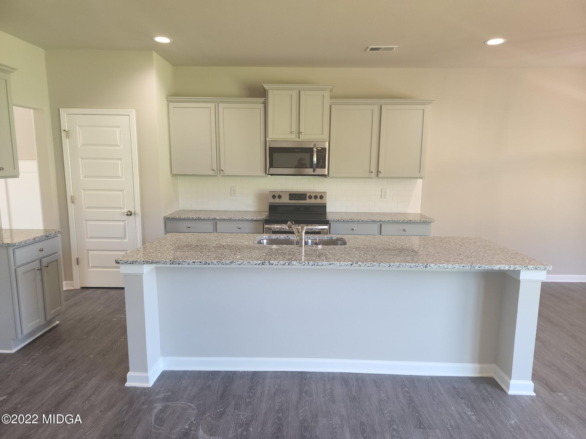 266 Presidents Way Forsyth, GA 31029 - Photo 3 of 21 a kitchen with stainless steel appliances granite countertop a sink a stove a refrigerator a microwave and cabinets