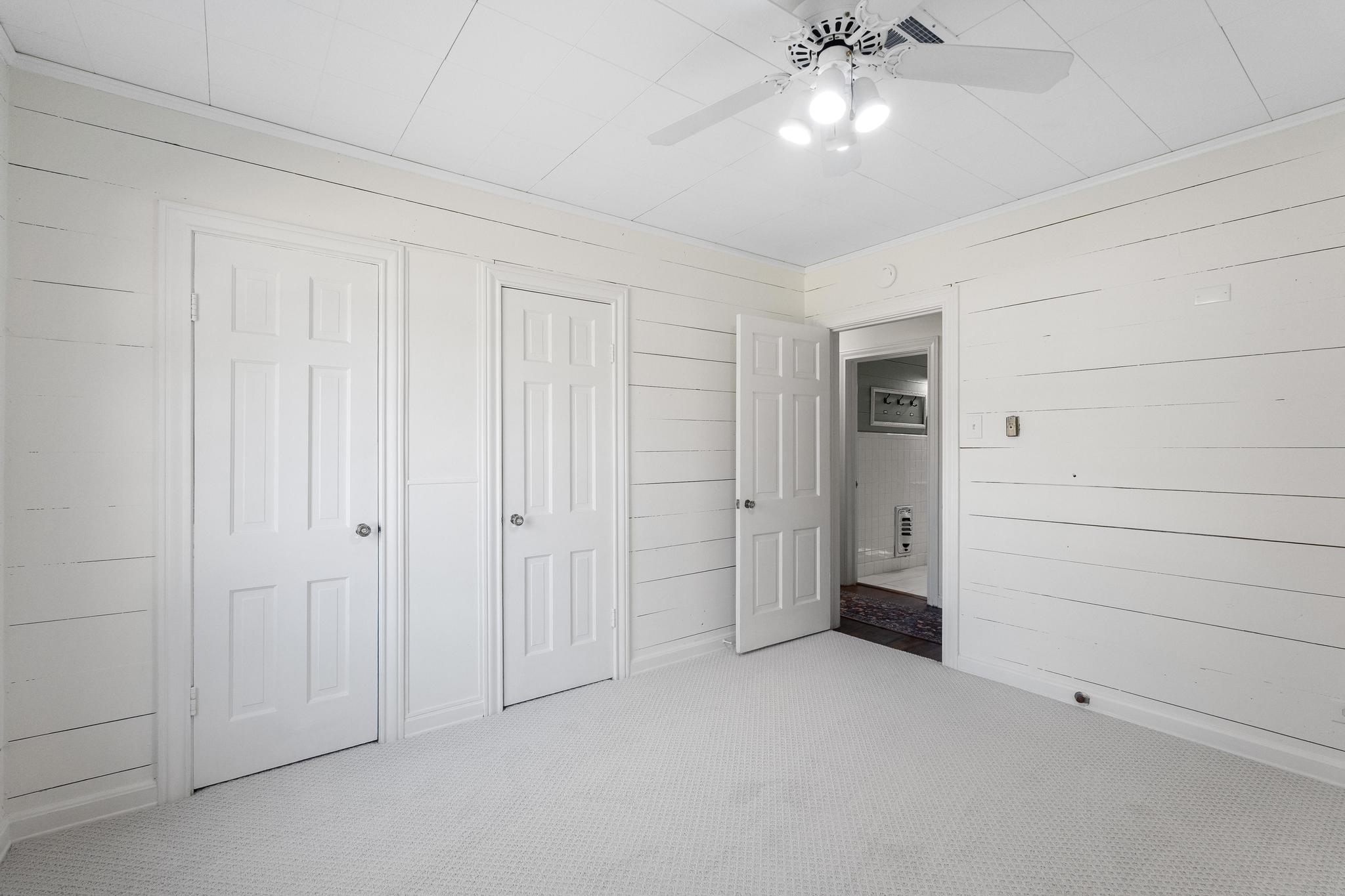 1707 Lexington Street Taylor, TX 76574 - Photo 20 of 29 Unfurnished bedroom with carpet floors, two closets, wooden walls, and a ceiling fan