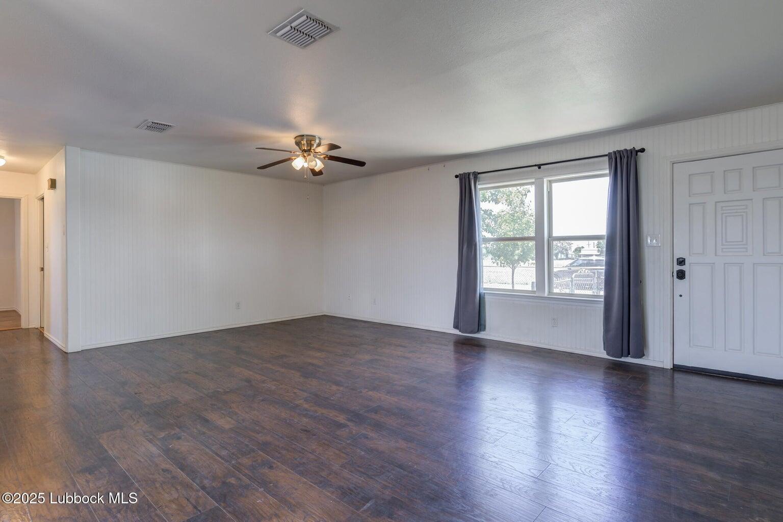 3506 Elm Avenue Lubbock, TX 79404 - Photo 3 of 12 an empty room with wooden floor chandelier fan and windows