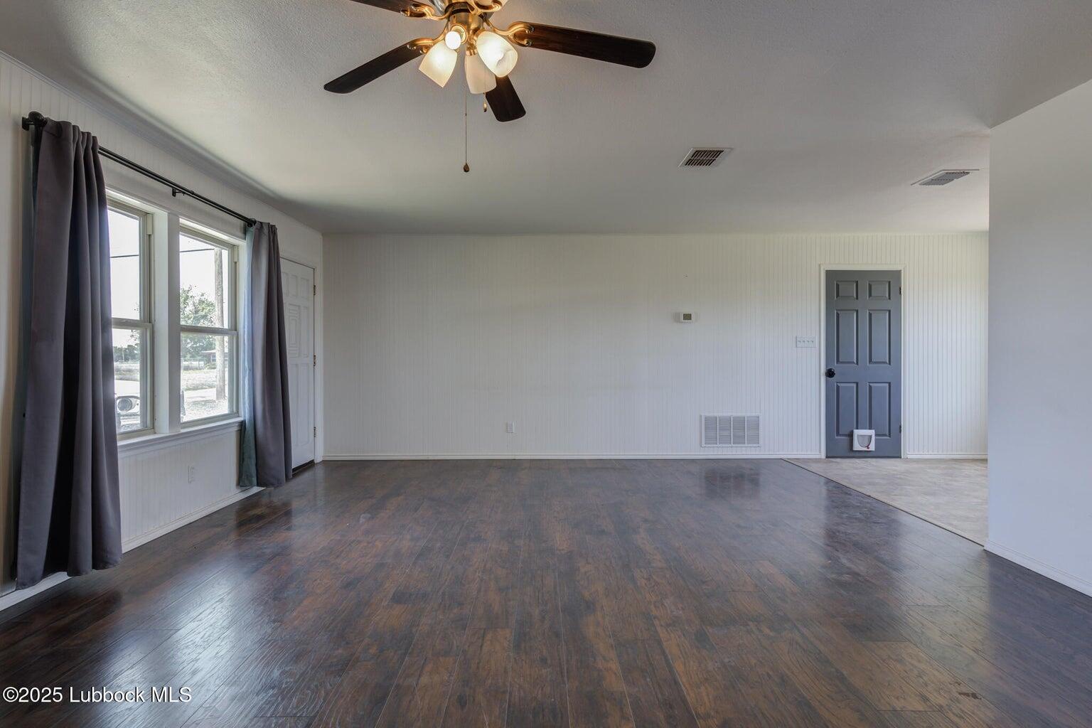 3506 Elm Avenue Lubbock, TX 79404 - Photo 6 of 12 an empty room with wooden floor chandelier fan and windows