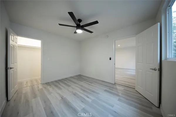 an empty room with wooden floor a ceiling fan and windows
