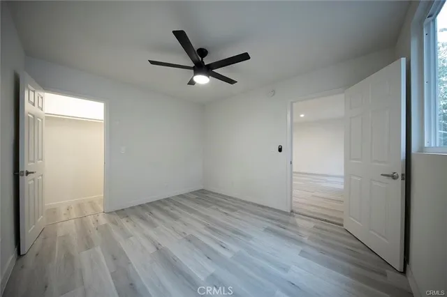 an empty room with wooden floor a ceiling fan and windows