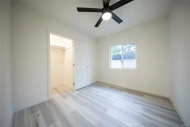 an empty room with wooden floor ceiling fan and windows