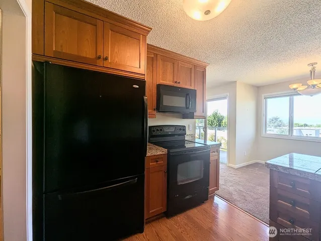 a kitchen with granite countertop a refrigerator stove and microwave