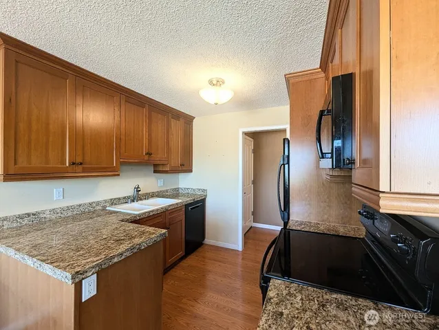 a kitchen with granite countertop stainless steel appliances a sink stove and refrigerator