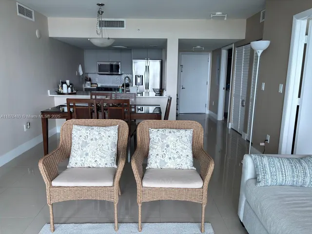 a living room with furniture kitchen view and a chandelier