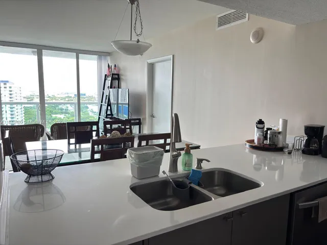 a kitchen with a sink a counter and living room view